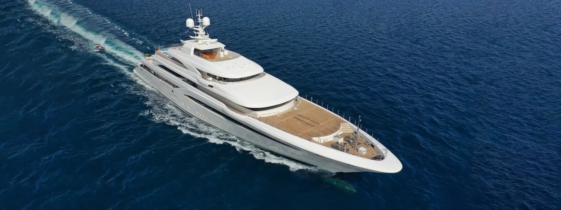 Aerial drone ultra wide panoramic photo of beautiful modern super yacht with wooden deck cruising in high speed deep blue open ocean sea